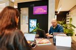 Man en vrouw zitten tegenover elkaar aan een bureau. Ze kijken allebei naar hun laptop.