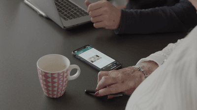 oude handen van een mevrouw en een telefoon op tafel