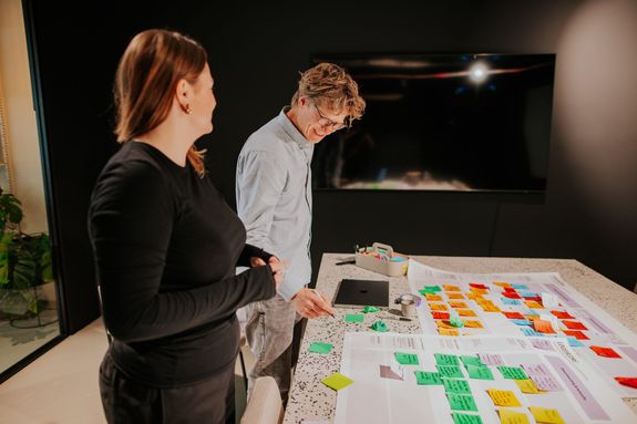 Man en vrouw staan bij een groot vel papier met allerlei post-its opgeplakt