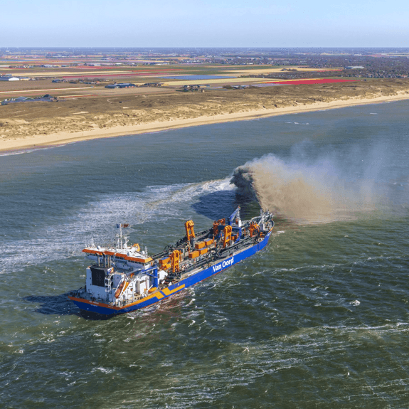 Een boot van Van Oord doet baggerwerk in de zee